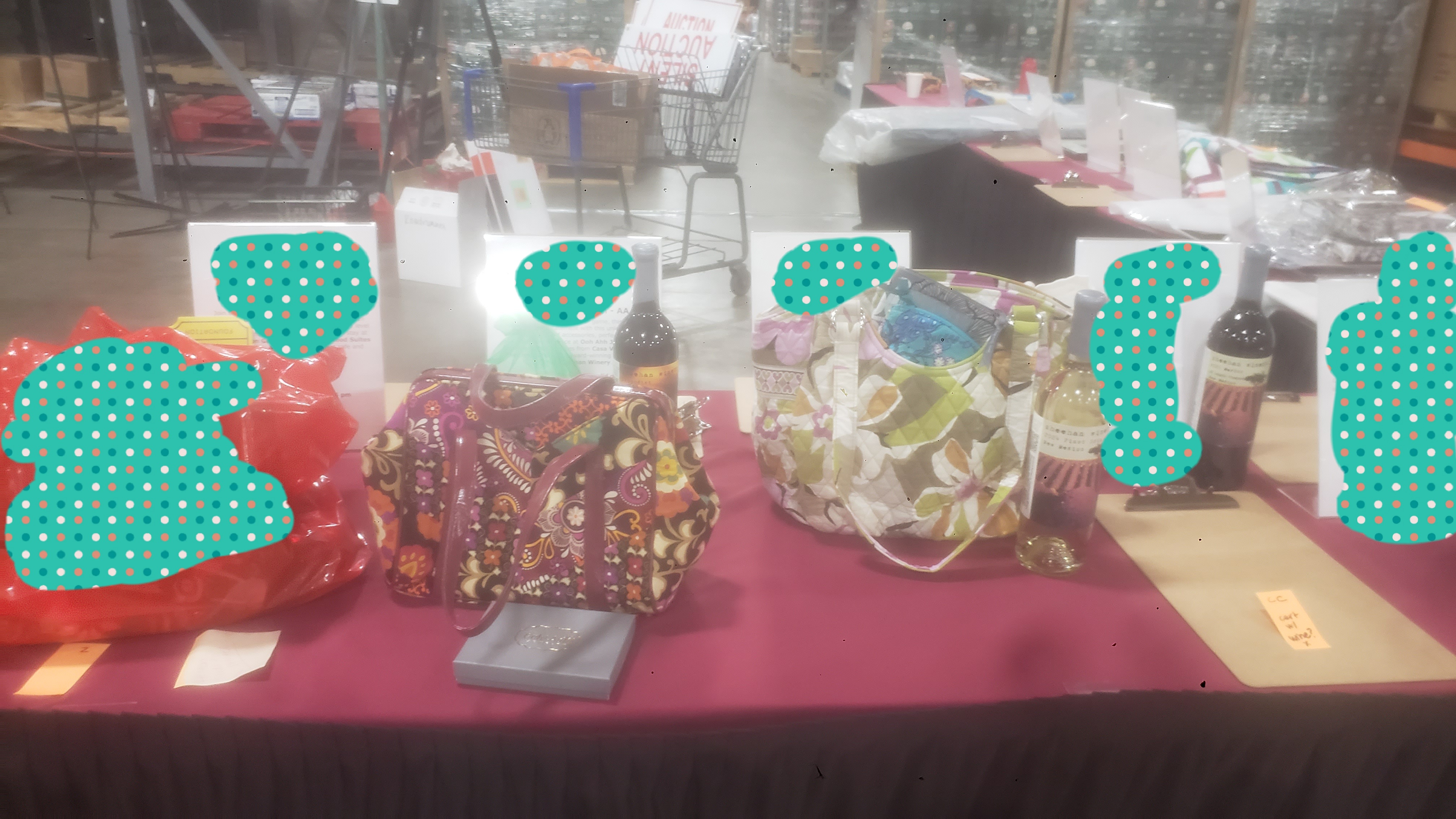 Silent auction items such as bags with wine on a table with signs.